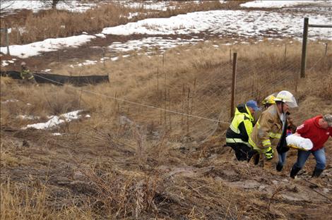 Emergency workers hold onto a cable to keep from slipping down a muddy ravine while carrying Stacie Rongwycsik-Lester to an ambulance. 