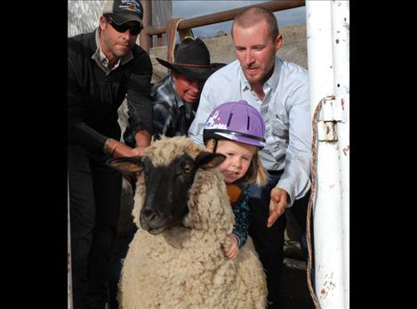 Madison Turner takes a turn in  the mutton bustin’ flanked by dad Stephen Turner, left, David  Graham  and Dillon Graham. 