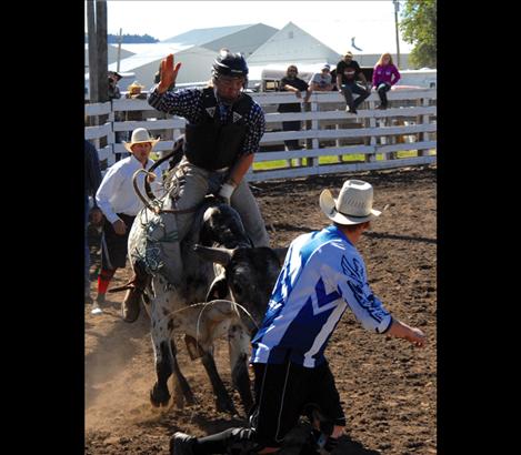 Polson high school athlete Bridger Fitzpatrick rides his bull as a rodeo clown gets out of the way.