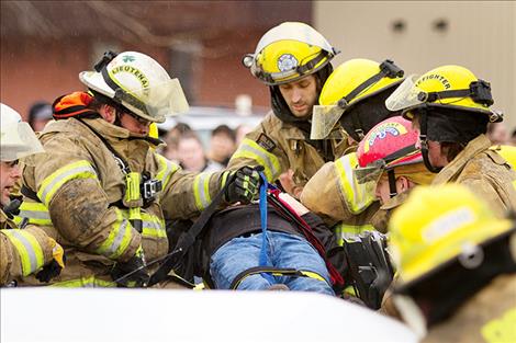 Ronan firefighters prepare a crash victim for transport.