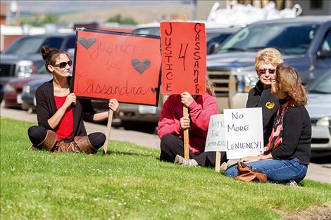 Protesters sit on the lawn outside the Lake County Courthouse and hold the signs they made. 