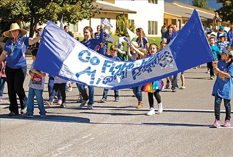 Left: Elementary students  carry a banner  with support  from teachers. 