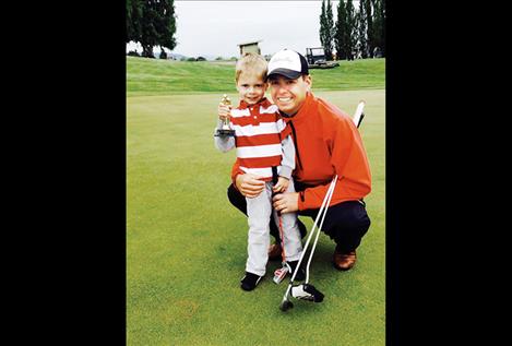 Cameron Milton, head golf professional for the Polson Bay Golf Course, poses for a photo with his son.