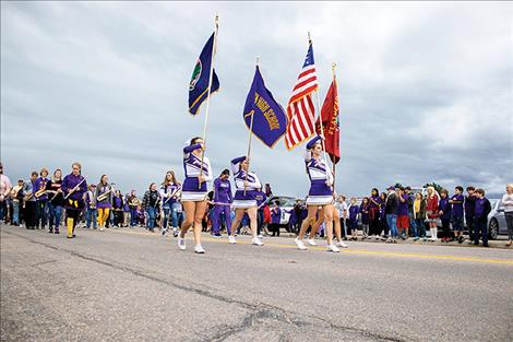 Polson High School students carry flags in the homecoming parade, followed by  several floats.