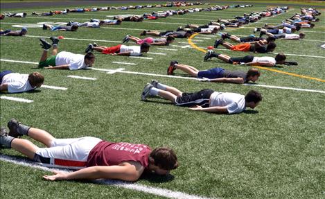 Ronan football camp participants do "up-downs" to warm up.