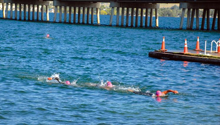 Three triathletes head for the docks at Riverside Park Saturday as they finish their 1.5 kilometer swim, only to head for their bicycles for round two.