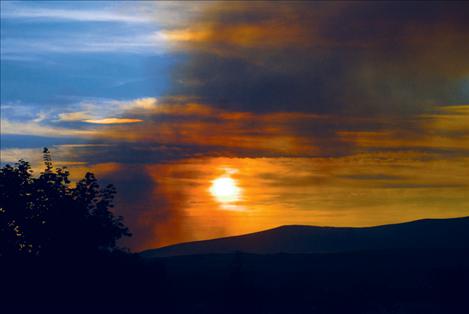 Smoke from the West Garcon fire spills over the foothills into the Polson area on the evening of Monday, Aug. 13.