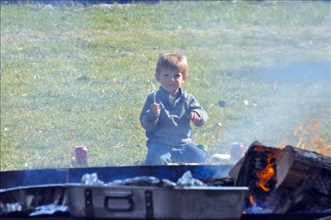 A boy eats in front of the fire at Bockman Park.