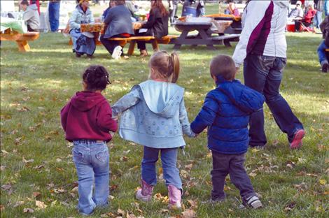 Maya St. Clair, Milee Cordier, and Xavier St. Clair hold hands at the Pig in the Park event.