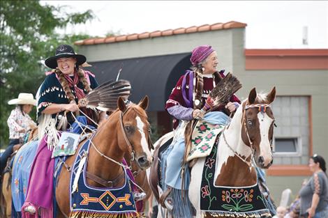 Pioneer Days parade participants smile from horseback.