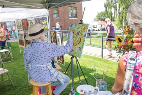 Artist Nancy Zadra paints flowers on a canvas at her booth during the 52nd annual Sandpiper Art Festival held on the county courhouse lawn.