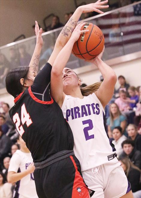 Polson Lady Pirate Julia Barnard is fouled on a drive to the basket during a Jan. 4 game against the Browning Lady Indians. Below: Pirate wrestler Jason Burrough works to pin his opponent during Jan. 4 