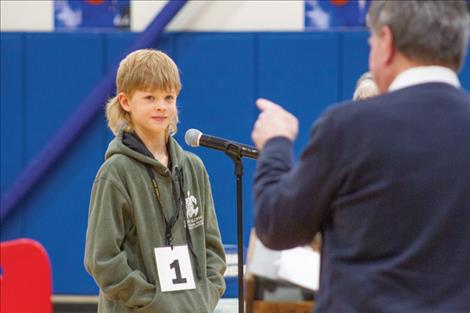 Ellis Stammers, sixth grader from Charlo, gets his first word from pronouncer John Lyons during the practice round. 