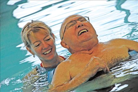 Chuck Lockwood floats in the therapy pool at Mission Valley Aquatics Center with a big smile on his face. Iinstructor Sharon Murphy guides him, and Chuck concentrates on moving his flippered feet. 