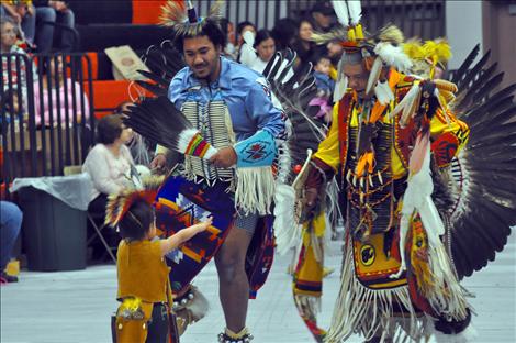 Ilan Skyuks, toddler, reaches out to older dancers at a Headstart Powwow.