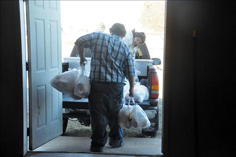 Joanne Shaw works with Kicking Horse Job Corps students to load bags of groceries that will be given to the elderly and small children.  