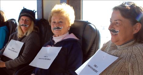 The three mustacheketeers — Heather Davies, left, Pat Cook and Donna Steele — support the office mates. 