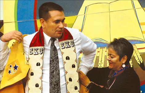 SKC President Robert DePoe III dons his new beaded buckskin vest with the help of JoJo Ducharme, member of the SKC Board of Directors. The board presented DePoe with the vest.