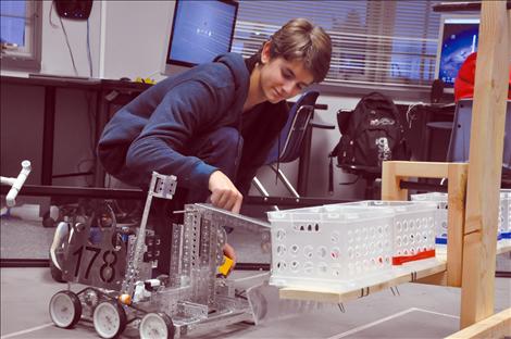 Tomasso Pieroncini works with a robot designed by the Ronan High School robotics team. 