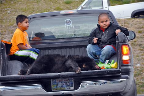 Aiden and Nateus Hewankhorn sit in the back of a truck with a juvenile black bear claimed by a tribal member after it was struck by a vehicle on 