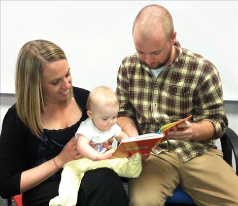 Lesley and Adam Fansher of Polson read to their young daughter. The couple received the book and a book bag with informational materials from the local Upsilon chapter of Delta Kappa Gamma when their daughter was born.