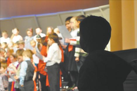 This silhouetted youngster crept up to the edge of the stage in an attempt to catch the eye of a friend performing in the  K. William Harvey Carol-Along. The bright stage lights proved a challenge and the small tyke never did get a wave back from any of the first and second grade performers.