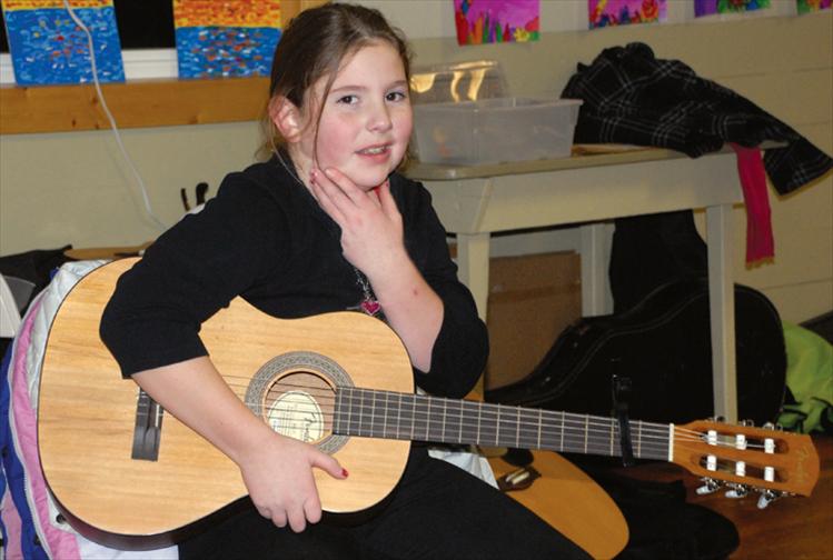 MaKenzie Walker holds her guitar as she gets ready to play with he schoolmates at the Valley View Christmas program on Dec. 19. This is the second year Valley View students have been playing guitar, last year was funded by a Plum Creek grant.