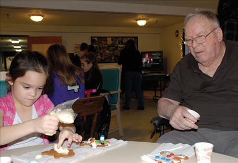 First grader Chloe Duncan frosts a cookie as an Evergreen resident looks on. 