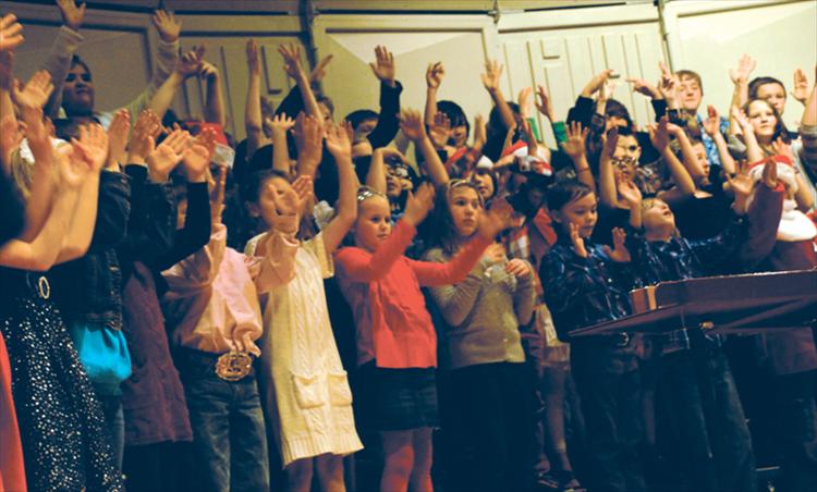 Signing as well as singing “Silent Night,” fourth graders end the holiday program on Dec. 19.