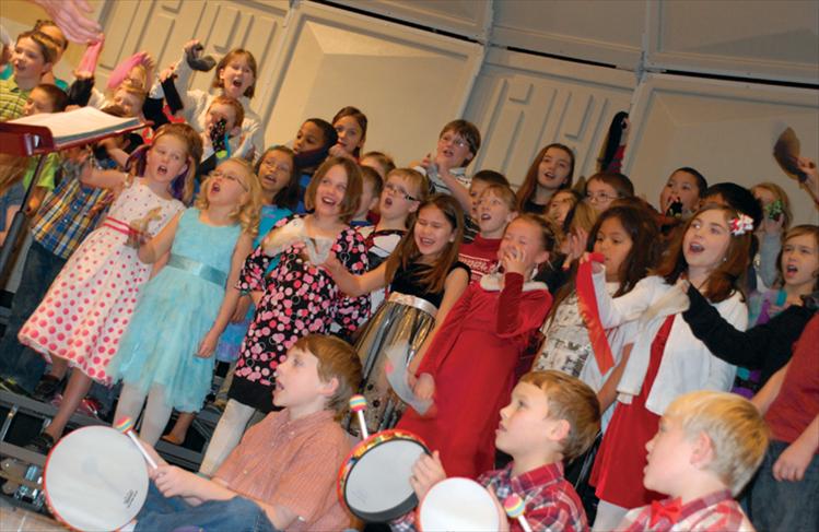 Third graders hold up socks as they sing a song about what they don’t want for Christmas — socks.