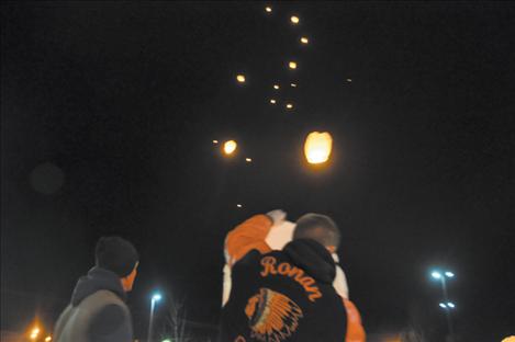A Ronan Student Council member holds a latern as others form an upward trail of floating beacons in honor of people separated from their families by distance or death this holiday season. 