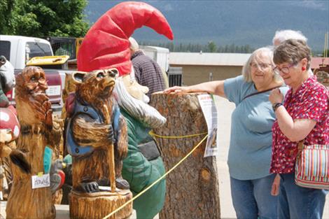 Chainsaw Carving Rendezvous spectators bid on items carved during the event at Sunday’s auction and peruse other works of art for sale brought by contest carvers.