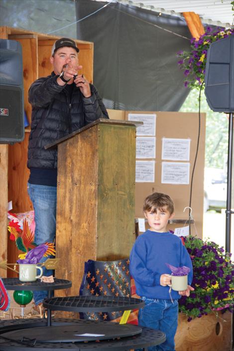 Auctioneer Travis Jeppeson points to a bidder while his son McKoy, 5, holds an auction item during the annual St. Ignatius Volunteer Fire Department picnic on Saturday, June 15.