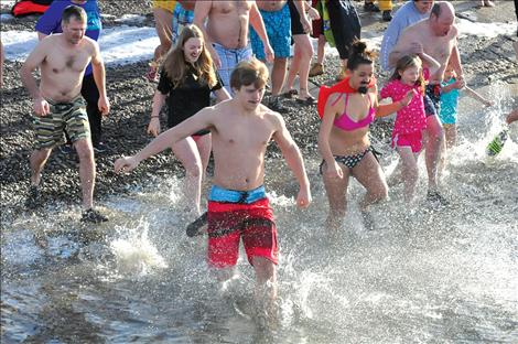 Josiah Edington barrels into the icy cold water to start off a new year with friends Laura Bahrs and Monica Cleveland. Nearby Taylor and Lauren Colligne hold the hand of Gary Collinge as they race into the water. 