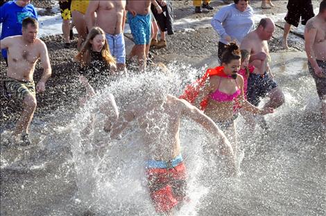 Josiah Edington barrels into the icy cold water to start off a new year with friends Laura Bahrs and Monica Cleveland. Nearby Taylor and Lauren Colligne hold the hand of Gary Collinge as they race into the water. 
