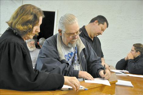 Roger Lemon, left, and Daren Incashola sign documents during the St. Ignatius Town Council meeting.