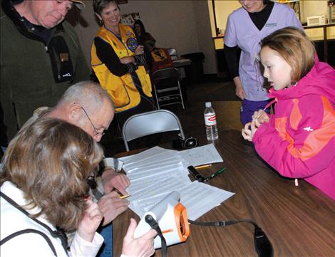 Colleen Sperry, left, Ken Cameron, Dennis DeVries, all from the Polson Lions Club, and Judy Lehman, Missoula Southside Lions Club search for Tyneesha Brown’s name on the list of students. Lehman spent three days inputting the data. 