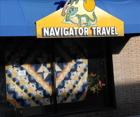 A huge sawtooth and star quilt hangs in the window of Navigator Travel during the quilt walk, bringing out the yellows and oranges in the travel agency’s sign.