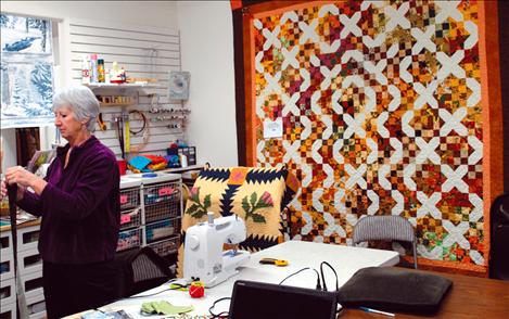 Quilts surround Susan Hartman as she teaches a class at All In Stitches.   