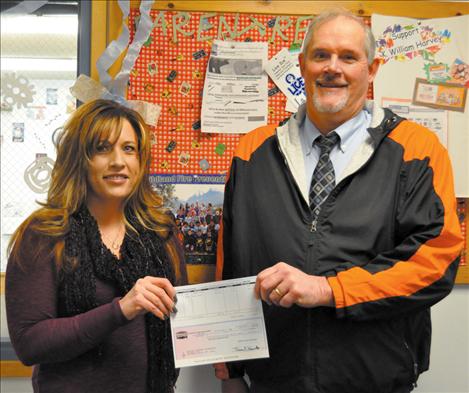 Town Pump District Manager Leslie Goss delivers a $500 check to K.William Harvey Elementary School Principal Ted Madden. 