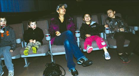 A family, with cups of juice and cereal bars, wait for “Despicable Me 2” to begin on Jan. 25.