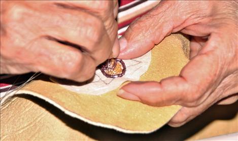 Geraldine Vallee Owen creates a flower design on a child’s buckskin moccasin.