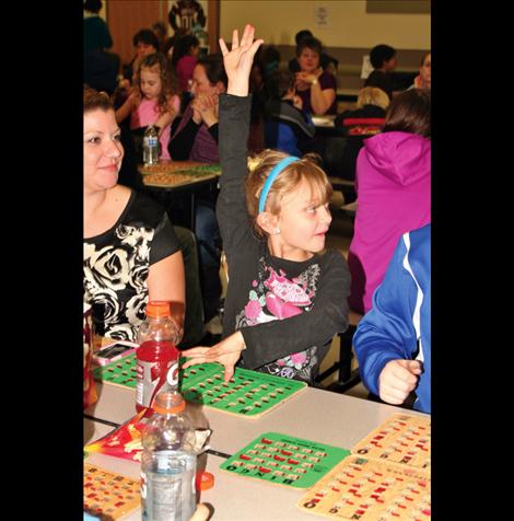 Lesli Bennett-Incashola, 7, raises her hand to announce to officials that she has a Bingo.