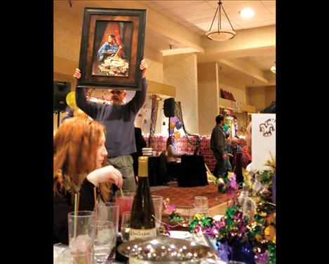 A combination of silent and live auctions is how funds are raised for the Boys and Girls Club of Lake County and Flathead Reservation during the annual Mardi Gras event. At left, a Karen Noles painting is held up for bid during the live  auction.