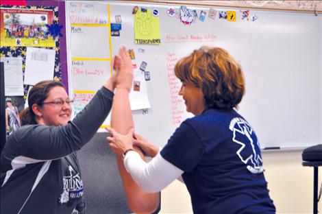 Valerie Umphrey high-fives with EMT Annie Morigeau using a training arm during a training exercise.