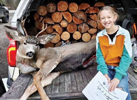 Lyla DeShazer sits on a tailgate with her first harvested deer at the Olney check station in northwest Montana. 