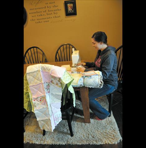 McKalistar Rosenbaum sews quilt squares at her family’s kitchen table in Charlo