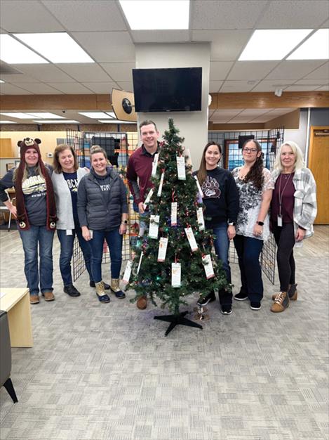Valley Bank-Polson staff stand next to a Friends of the Children giving tree in their lobby. Each tag on the tree represents a child and includes gift wishes to help them feel cared for during the holidays.