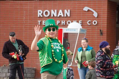 A participant in last year’s St. Patrick’s Day parade waves as he walks down Main Street, Ronan.