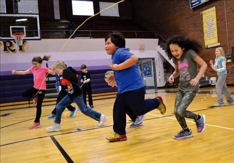 Children run through a large jump rope, hoping to avoid getting tangled.